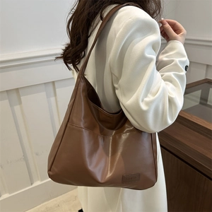 Borsa tote retrò marrone scuro con tasca frontale e tracolla indossata da una modella
