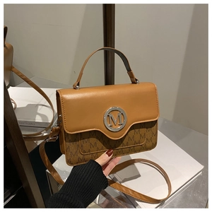 Detailed shot of brown leather bag featuring an M logo and adjustable strap