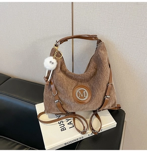 Détail d'un sac d'épaule en velours côtelé marron avec logo M et charme en peluche