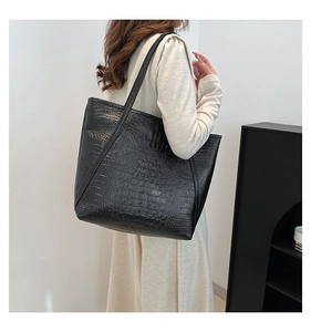 Close-up of black crocodile embossed tote bag with glossy finish and slim shoulder straps