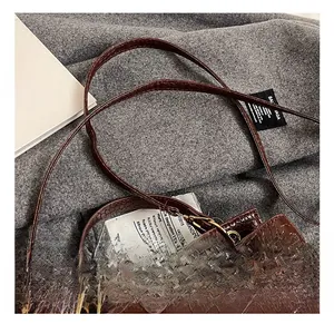 Détail d'un sac à main marron foncé motif crocodile avec fermoir rotatif en métal doré