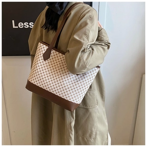Model wearing a large patterned tote bag with brown leather trim and geometric prints