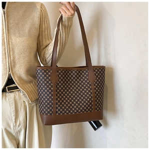 Close-up of retro tote bag featuring brown geometric pattern and durable leather handles