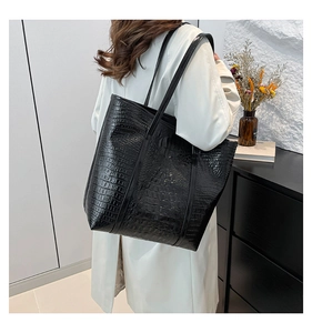 Close-up of black crocodile pattern faux leather tote bag on model's shoulder