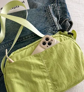 Dettaglio della borsa a tracolla verde chiaro con tasca frontale e spazio per lo smartphone