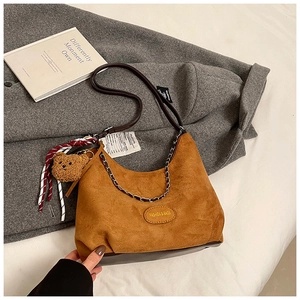 Dettaglio borsa hobo in camoscio caramello con tracolla a righe e ciondolo orsetto