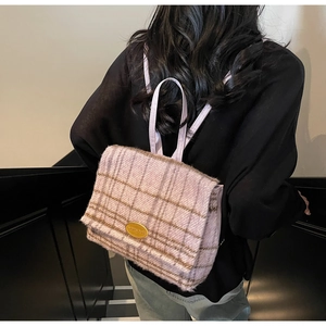 Détail du sac à dos en laine à carreaux lavande avec logo doré et lanières en cuir