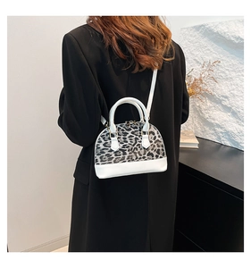 Detail view of leopard print shell bag with white leather handle and metal zipper