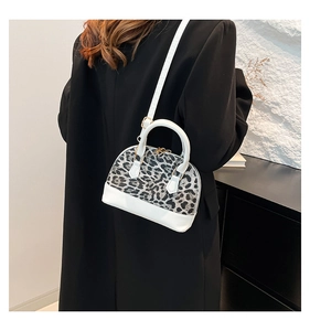 Detail of leopard print shell bag featuring white faux leather base and adjustable strap