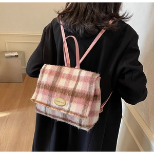 Détail du sac à dos en laine à carreaux roses montrant la texture et la plaque dorée