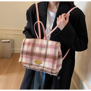 Détail du tissu en laine à carreaux roses et logo en métal doré du sac à dos d'hiver
