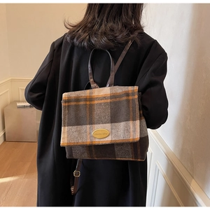 Détail d'un sac à dos vintage en laine à carreaux sur un mannequin en manteau noir