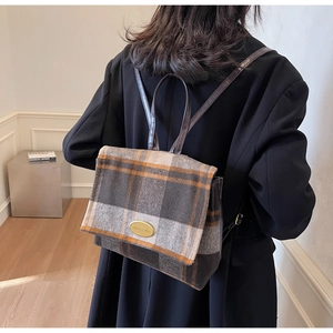 Détail du rabat en laine à carreaux et logo doré sur le mini sac à dos de voyage femme