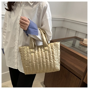 Detalle del bolso tote acolchado dorado metalizado con costuras verticales y textura suave