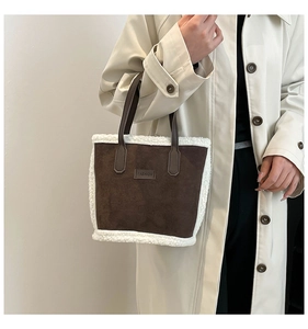 Dettaglio borsa a secchiello in camoscio marrone con bordo in peluche e etichetta FASHION