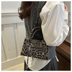 Dettaglio della borsa leopardata con bordi bianchi a contrasto e zip decorativa frontale