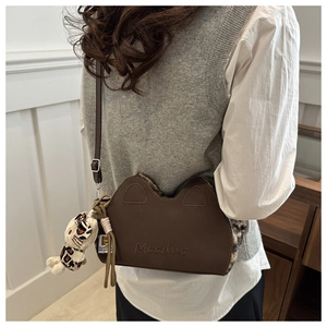 Détail d'un sac à bandoulière chat marron avec peluche léopard et breloque mignonne
