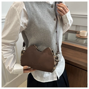 Détail d'un sac bandoulière en cuir marron avec oreilles de chat et fausse fourrure