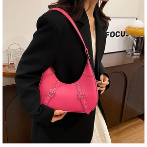 Detail der pinken Halbmond-Schultertasche mit Metallgurten auf schwarzem Blazer