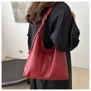 Model wearing a retro deep red oversized matte leather hobo bag with wide shoulder strap