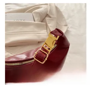 Detail of polished gold hardware and luxury burgundy leather on the crescent bag