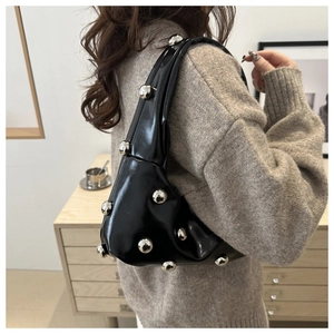 Détail du sac à bandoulière en cuir verni noir avec rivets boule argentés et texture plissée