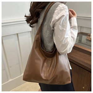 Dark brown matte leather tote bag shown on model with minimalist vertical seam detail