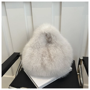 Detail of soft white faux fur handbag texture with integrated plush handle on book