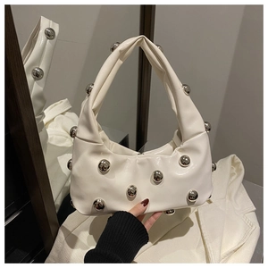 Détail d'un sac hobo blanc avec rivets argentés et finition brillante sur surface miroir
