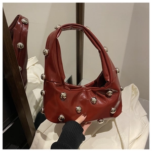 Détail du sac à main rouge foncé brillant avec clous métalliques argentés et forme hobo