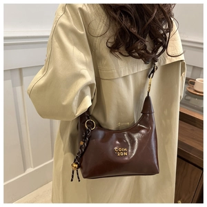 Detail of glossy dark brown crescent bag with gold COIH 2DN logo and slim shoulder strap
