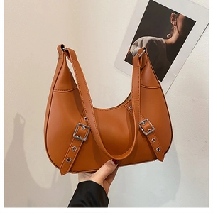 Nahaufnahme der orange-braunen Mondsichel-Tasche mit modischen Metall-Schnallen