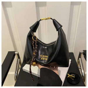 Detail of black glossy crescent bag with gold logo, decorative knot and hardware buckle
