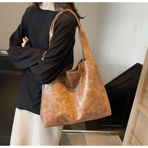 Detail view of large brown vintage textured leather tote bag with wide shoulder strap