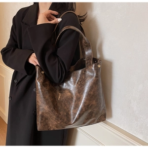 Close-up of vintage brown leather tote bag with metallic rivets and crackle texture