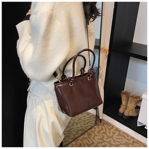 Detailed view of the dark brown patent leather tote bag with glossy finish and gold hardware