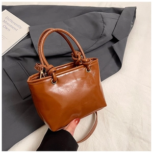 Detail of caramel brown mini bucket bag showing knot handle design and smooth leather texture