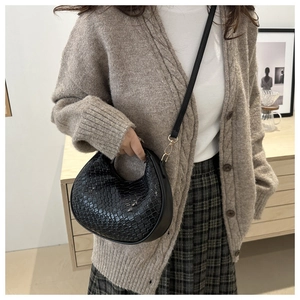 Détail du sac hobo tissé noir avec boucle en métal doré et bandoulière en cuir