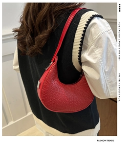Detail of red woven crescent underarm bag showing texture and silver metal hardware