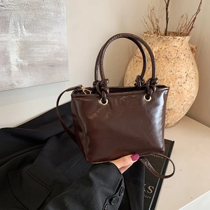 Dark brown PU leather bucket bag with knotted handle and golden metal eyelets detail