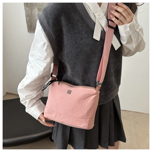 Sac bandoulière rose en toile avec sangle réglable et logo trèfle porté par un mannequin