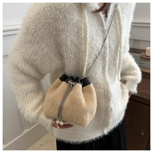 Detalle del bolso tipo saco de felpa beige con cadena de metal y borlas de perlas