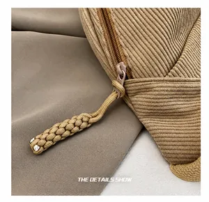 Detail of the corduroy handbag featuring a smooth zipper and a braided rope puller