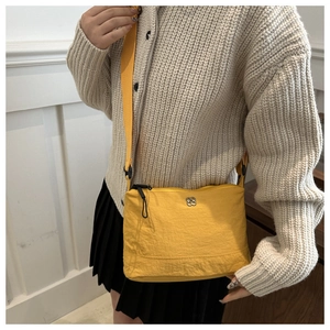 Détail d'un sac bandoulière jaune en nylon avec fermoir fleur et bandoulière en textile