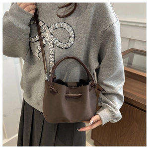Detail of vintage coffee bucket bag with decorative side knots and matte leather finish