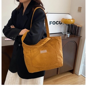Close-up of ginger yellow corduroy tote bag with front pocket and XINRUIGOOD label