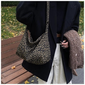 Sac hobo chic à imprimé léopard porté par un mannequin dans un parc extérieur