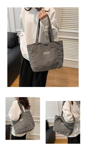 Detail view of large dark grey corduroy tote bag with side pocket and woven label