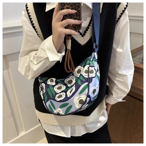 Detail of printed canvas crescent bag with white floral pattern and blue strap