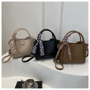 Detalle de bolsos tipo cubo de invierno en beige, negro y marrón con pañuelos decorativos